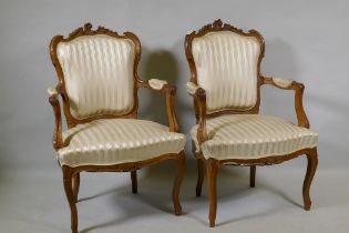 A pair of C19th French carved beechwood open armchairs with shaped backs, raised on cabriole