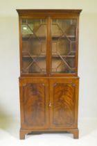 A small Georgian style mahogany bookcase in two sections, the upper with astragal glazed doors,