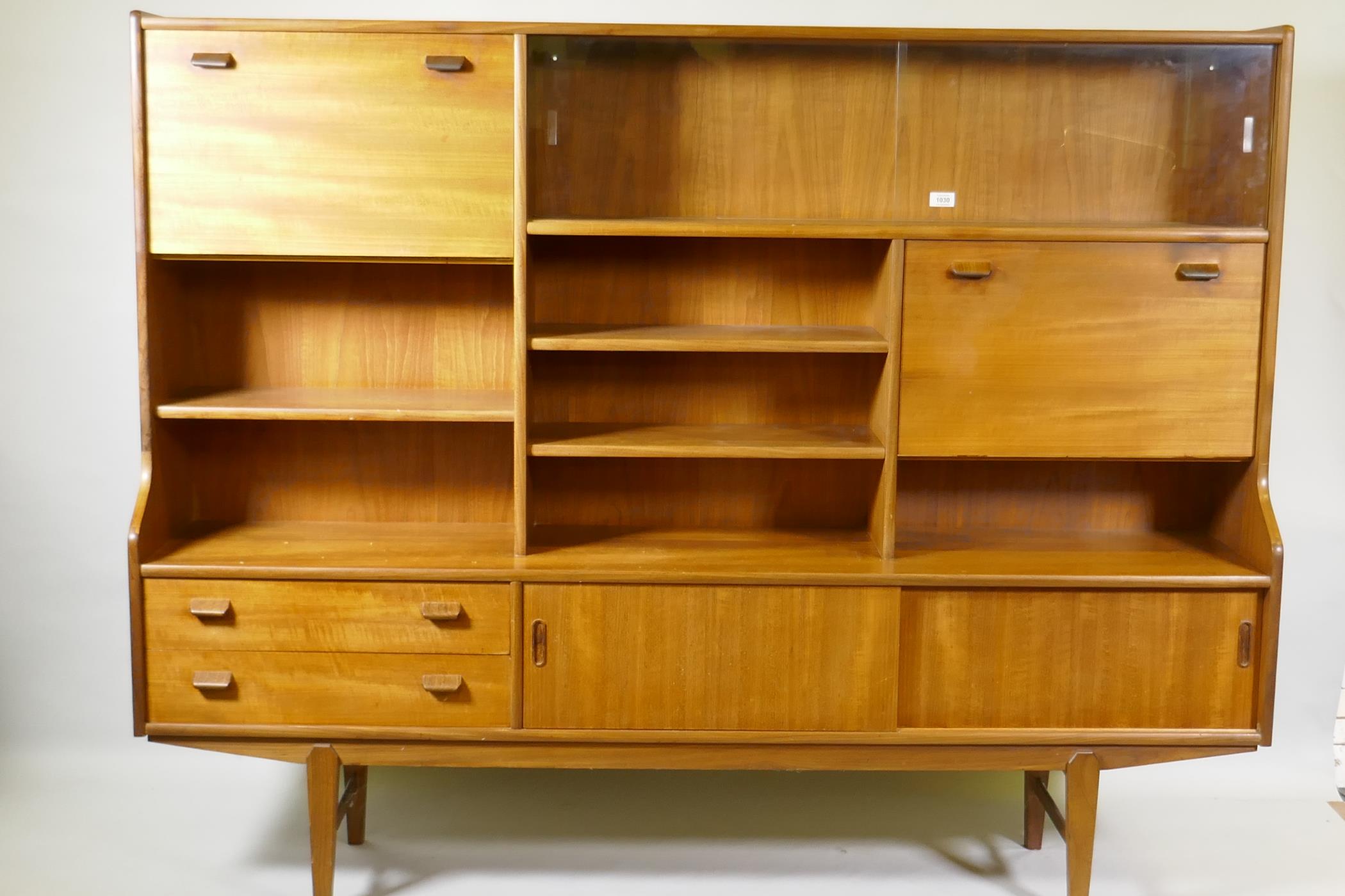 A mid century teak side cabinet with sliding glass doors and open shelves over two drawers and