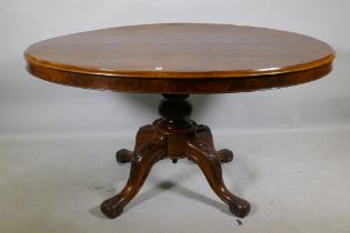 A Victorian figured walnut tilt top breakfast table, the oval top raised on a carved and turned