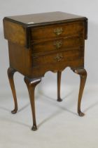 An early C20th Georgian style walnut work table, with drop flaps and three drawers, raised on