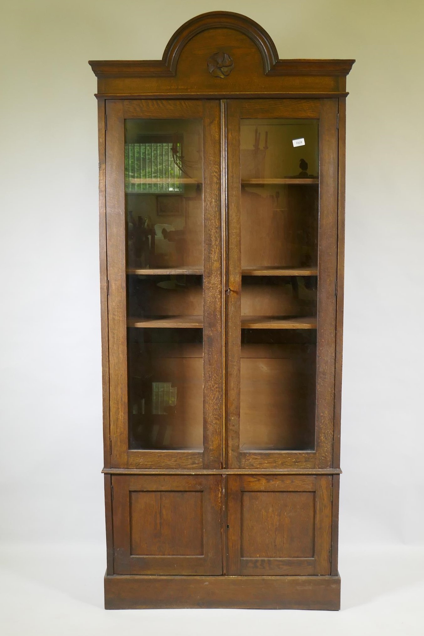 A C19th oak cabinet with arched top and two glazed doors over two cupboards, 90 x 30 x 210cm