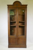 A C19th oak cabinet with arched top and two glazed doors over two cupboards, 90 x 30 x 210cm