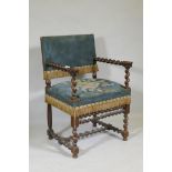 A Jacobean style walnut open armchair with barley twist and carved lion decoration, studded tapestry