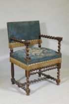 A Jacobean style walnut open armchair with barley twist and carved lion decoration, studded tapestry