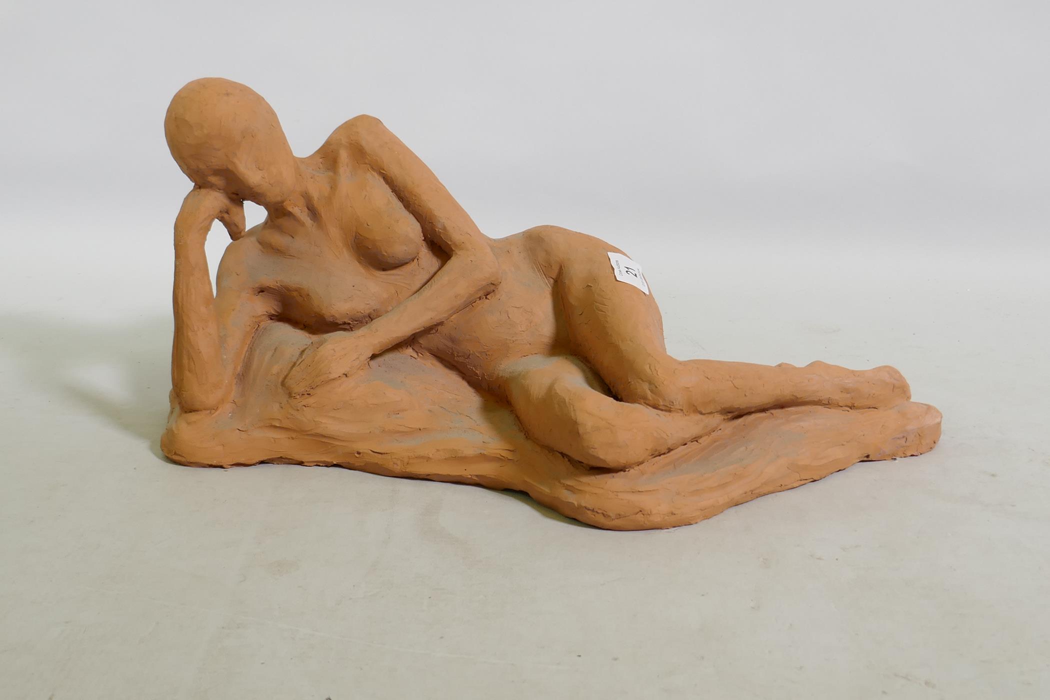 A terracotta sculpture of a reclining nude, inscribed MJ 94, 46 x 21cm