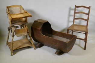An antique oak cot, a child's metamorphic chair and a cane seated child's chair, cot 88cm long