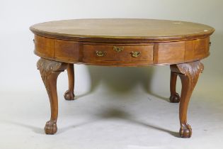 A Georgian style oak library/drum table with four drawers, raised on cabriole supports with carved