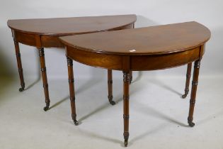 A pair of Georgian mahogany demi lune side tables with moulded edge tops, raised on ring turned