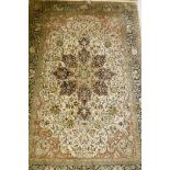 An Oriental silk carpet with floral designs and central medallion on a cream and faded terracotta