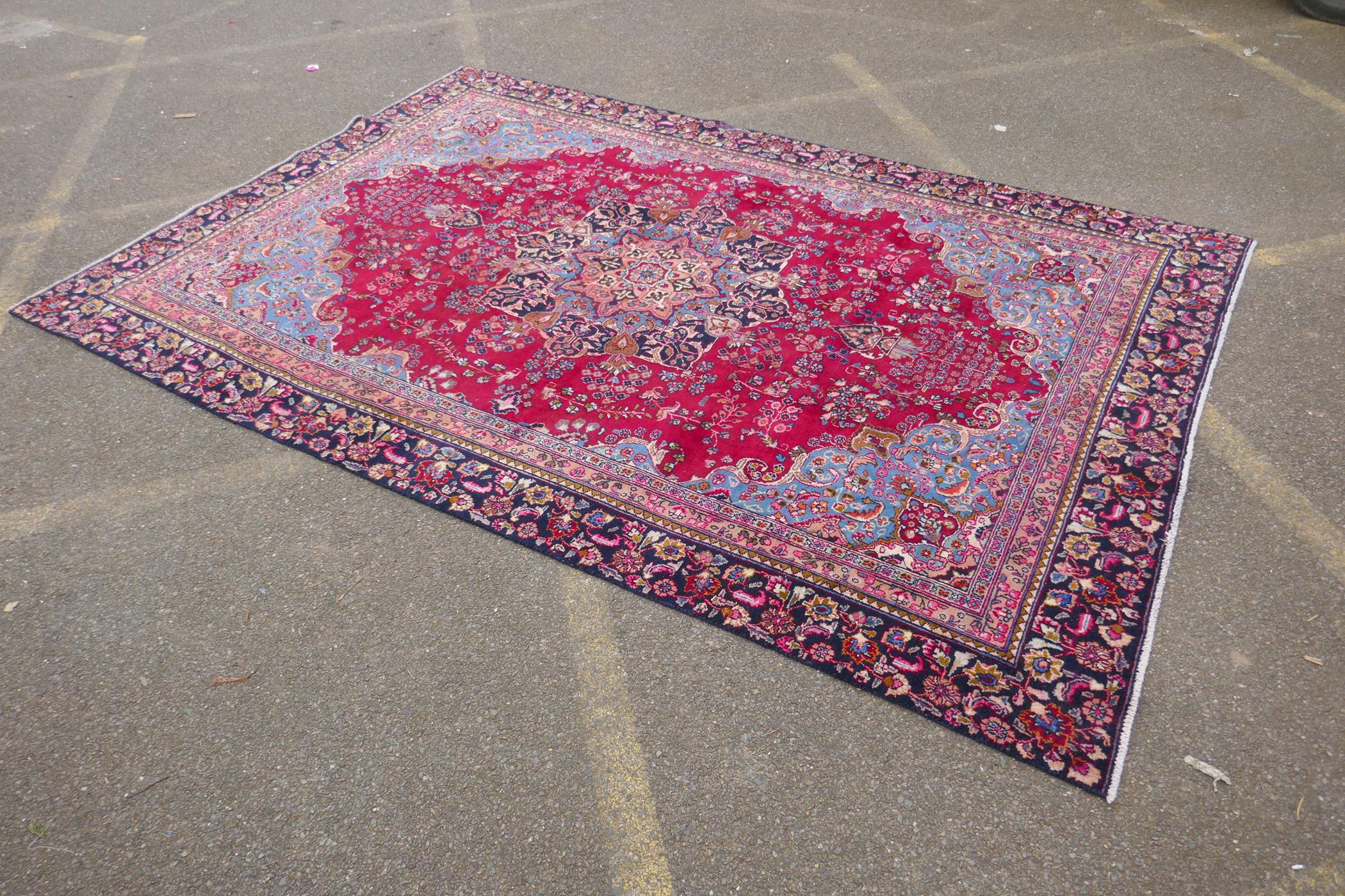A claret and blue ground Persian Mashad carpet with a traditional floral medallion design, - Image 2 of 6