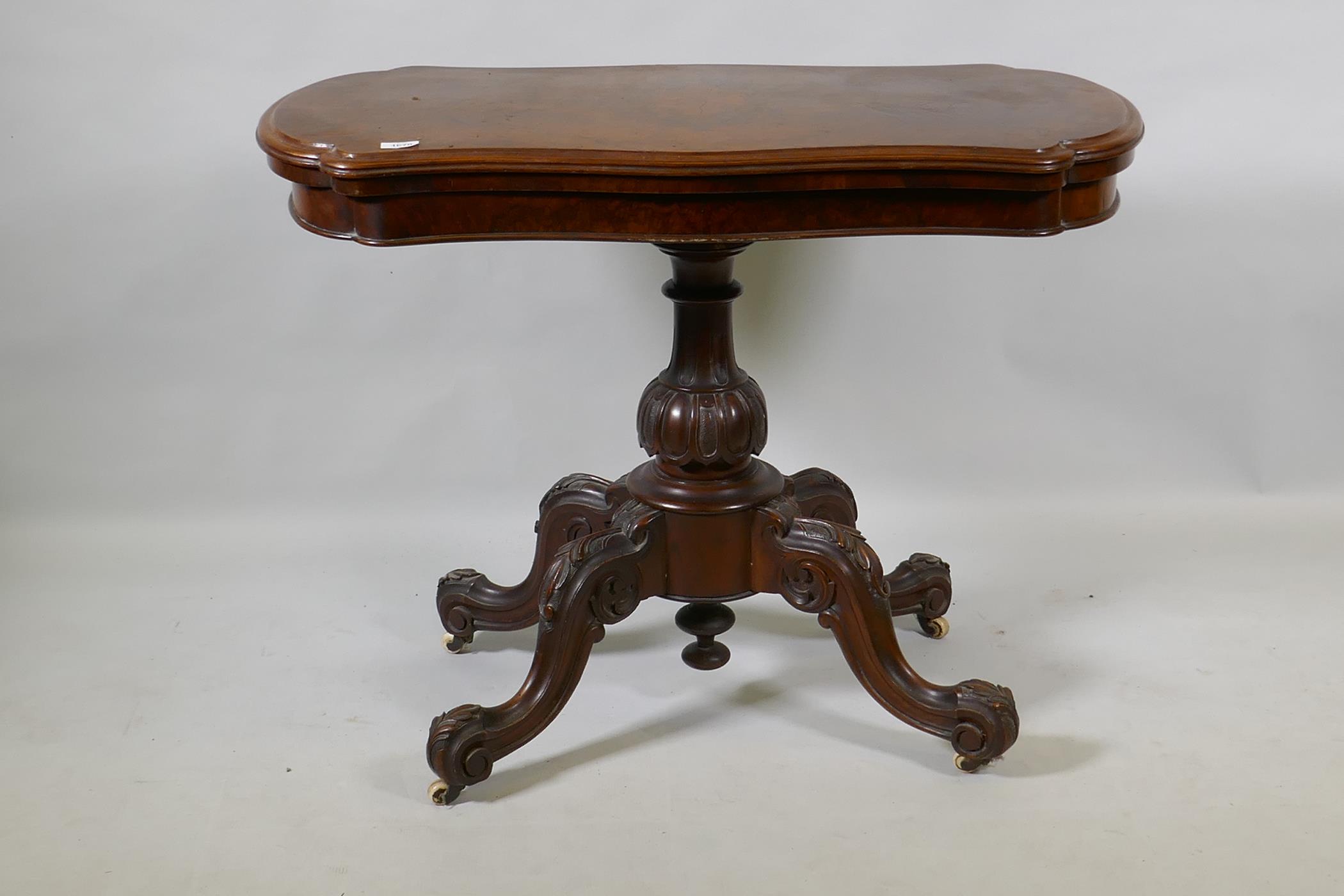 A Victorian burr walnut shaped top card table, raised on a carved and turned column and cabriole