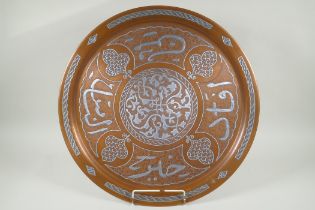 An Islamic silver overlaid copper tray with caligraphic script decoration, 55cm diameter