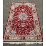 A fine woven full pile rich red ground Qom carpet, with floral medallion design and floral