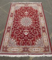 A fine woven full pile rich red ground Qom carpet, with floral medallion design and floral