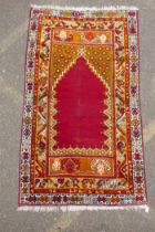 A rich red ground Caucasian rug with prayer mat design and multi-colour borders, 112 x 186cm