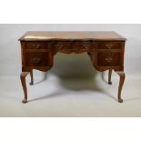 A Georgian style walnut five drawer kneehole desk with inset leather top, raised on cabriole
