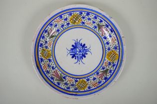 An antique Delft plate decorated with a floral design, 32cm diameter