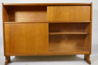 A mid century Nathan teak bookcase with open shel and fall front over two sliding doors, raised on