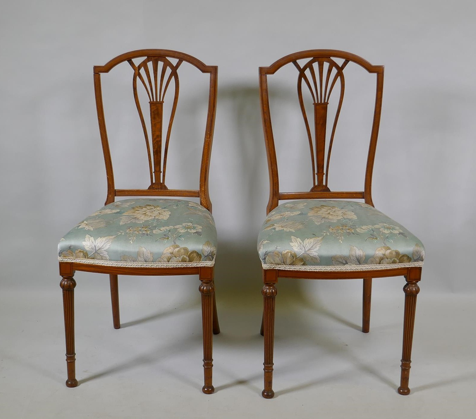 A pair of Victorian satinwood bedroom side chairs with pierced splats, raised on reeded supports (