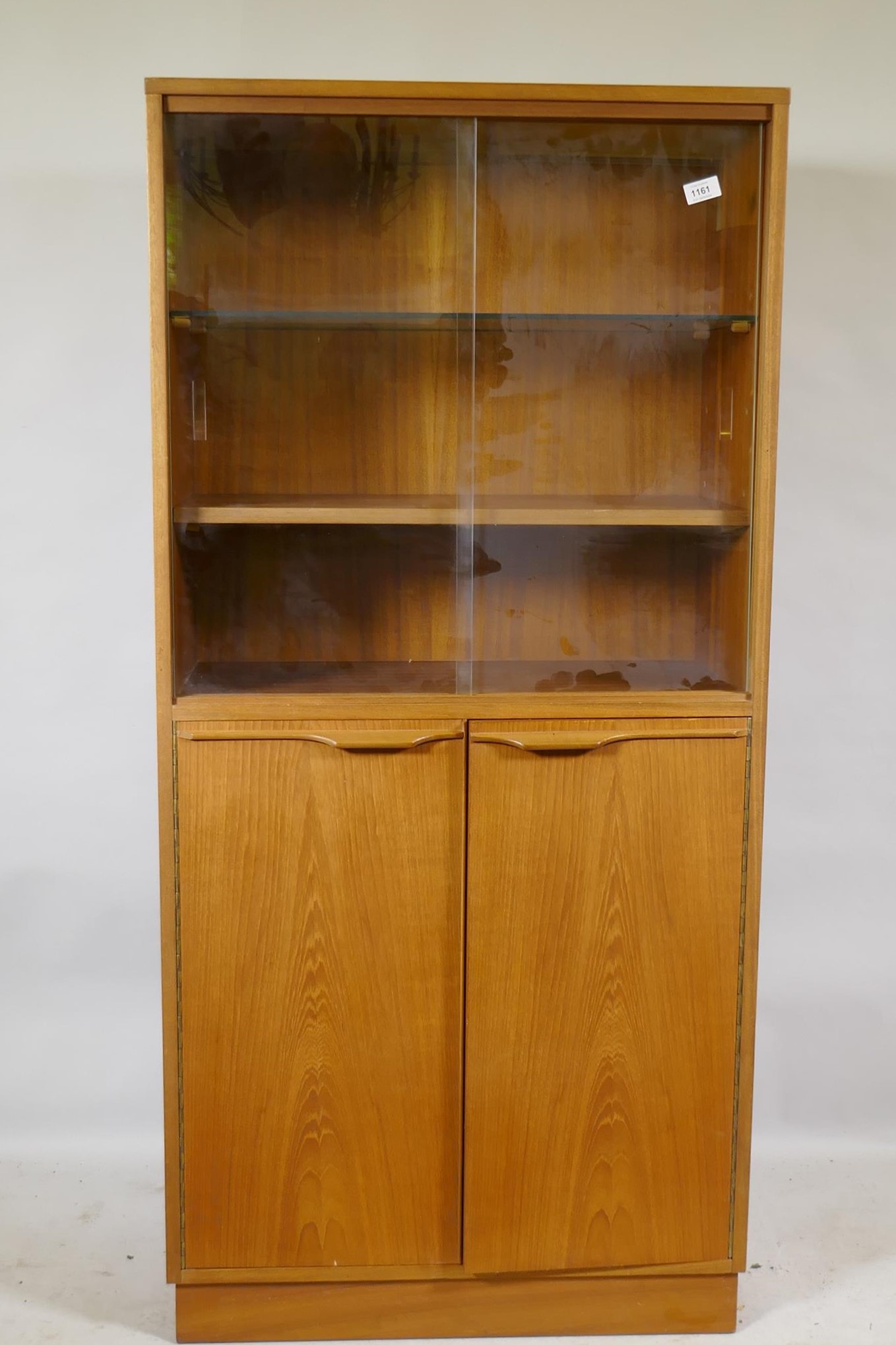 A mid century teak cabinet, with sliding glass doors over two cupboards, 69 x 36 x 144cm