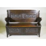 A Victorian oak monk's bench, with two panel fold over top, lift up seat and panelled front with