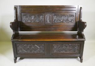 A Victorian oak monk's bench, with two panel fold over top, lift up seat and panelled front with