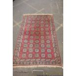 A hand woven Caucasian carpet with a bespoke all over Bokharra design on a salmon pink ground, 185 x