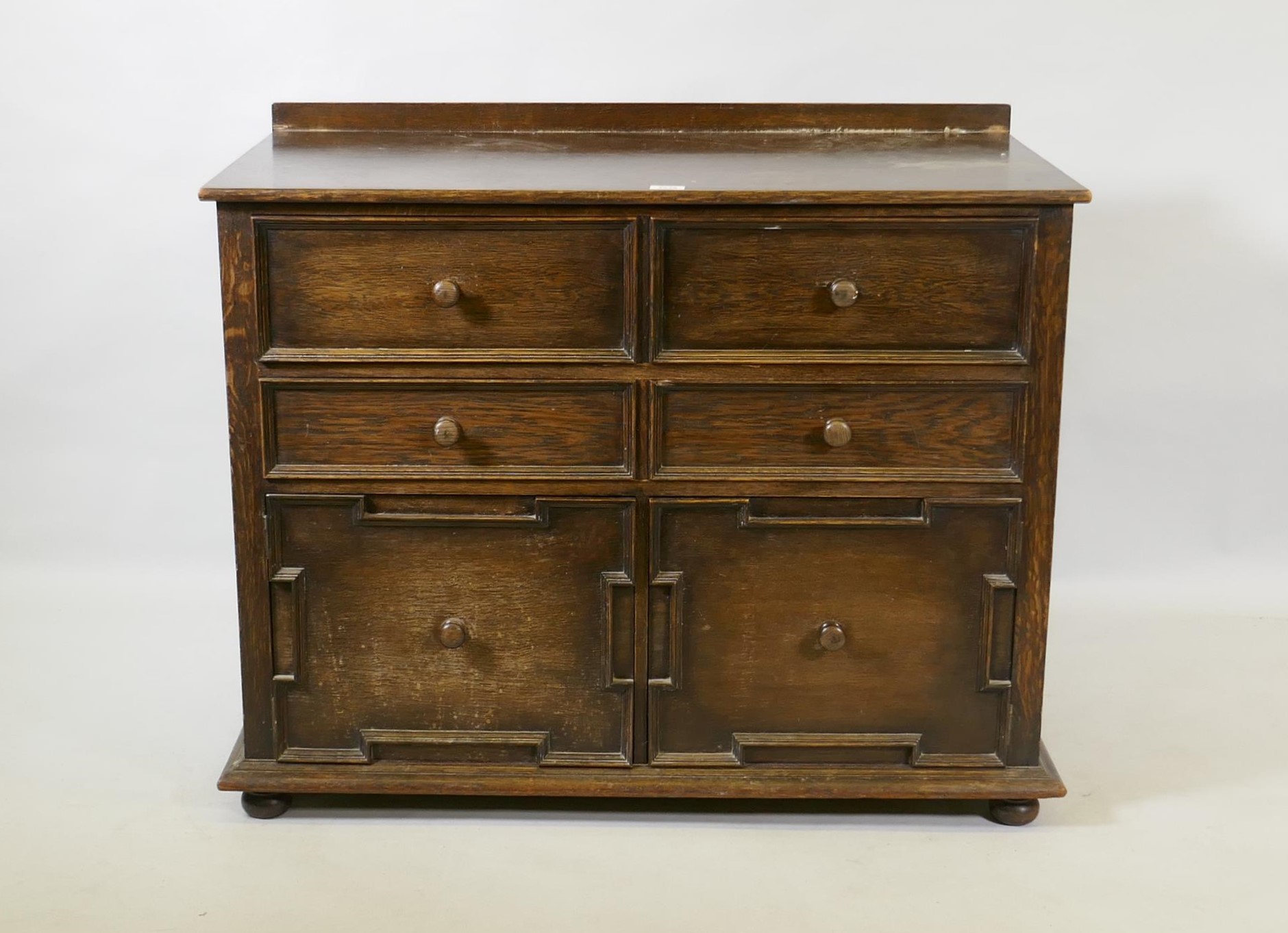 A Jacobean style oak cabinet, the top drawer with fold down front over a single drawer and two