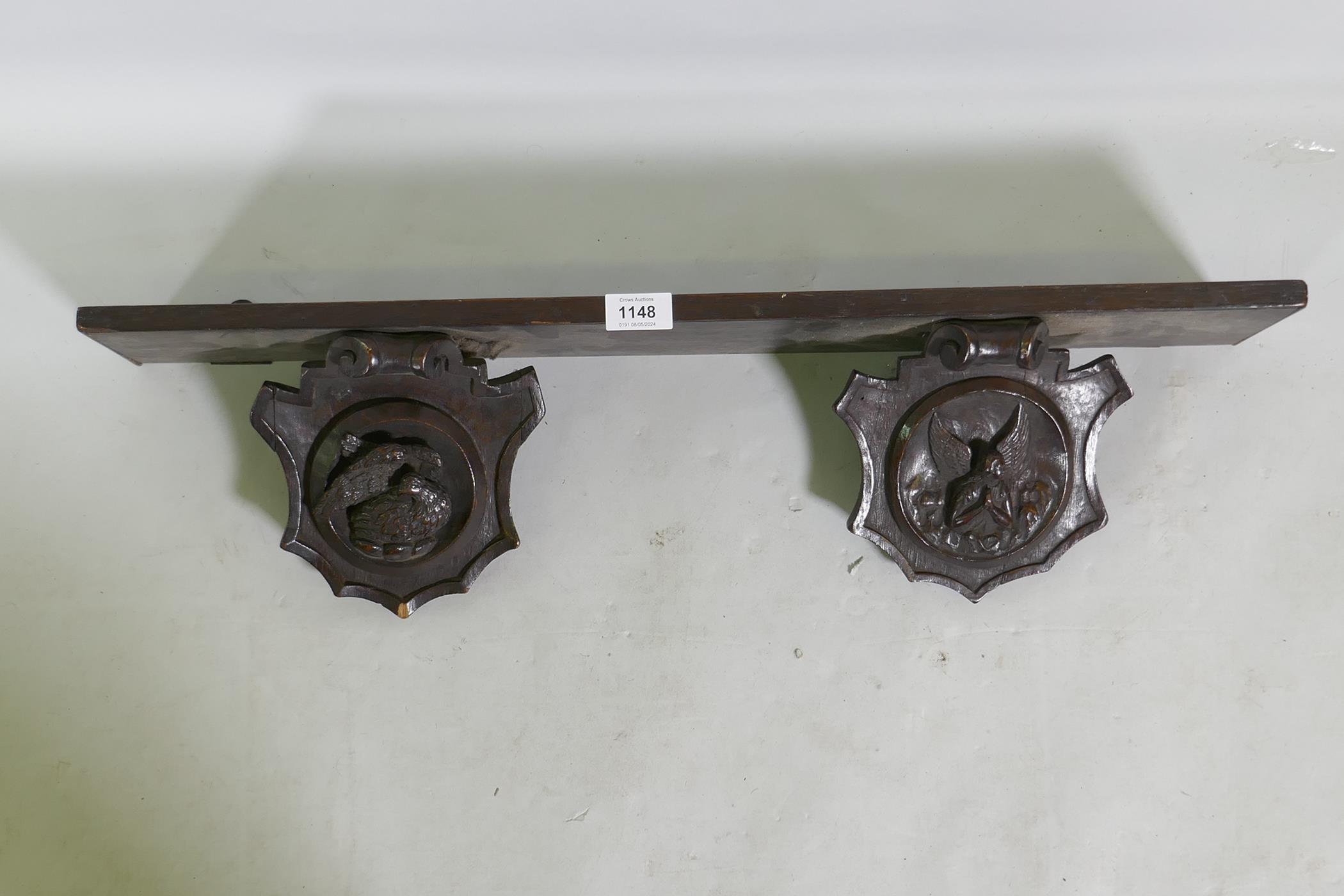 An C18th/C19th French oak shelf with carved brackets decorated with a bird and an angel, 72 x 13 x