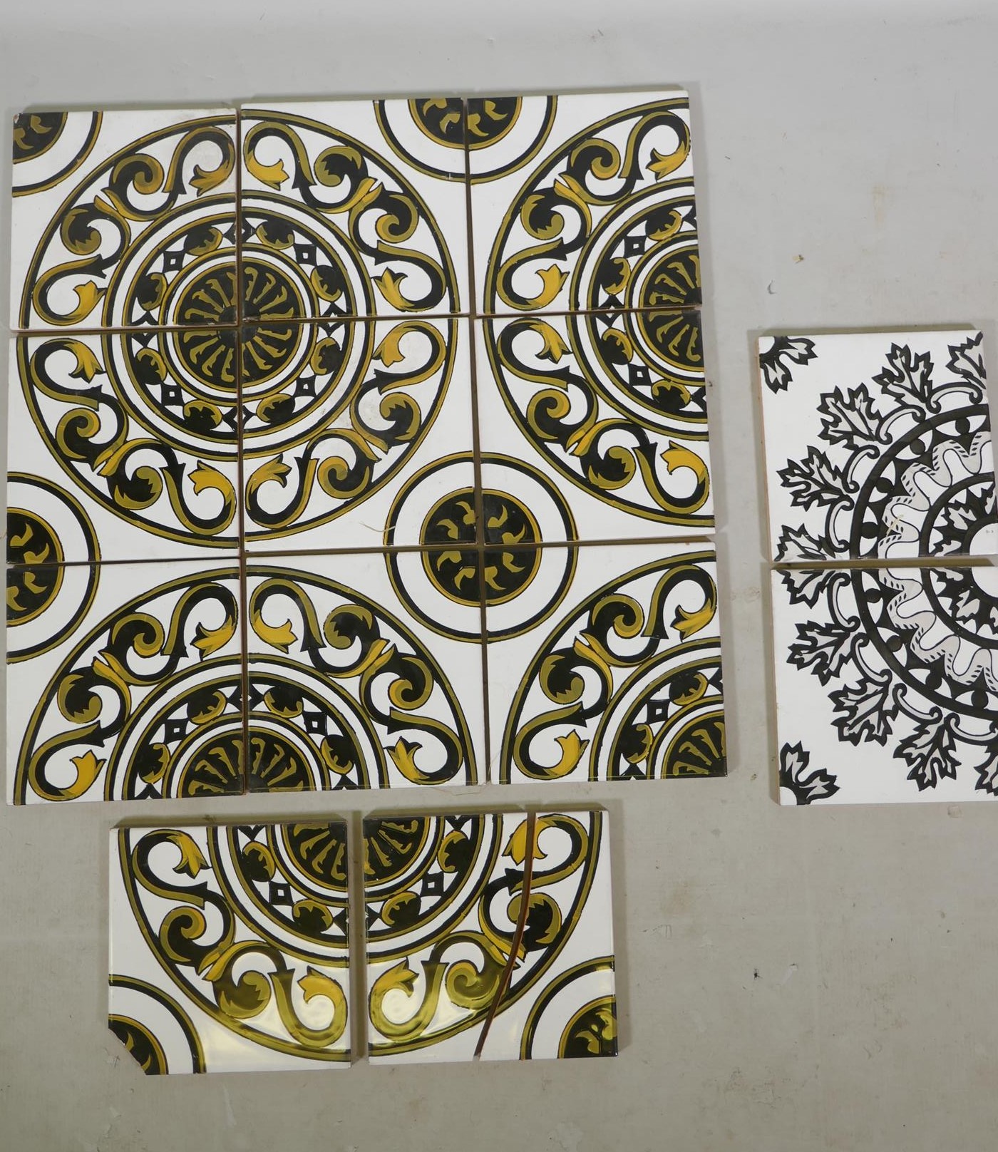 Eleven Spanish terracotta tiles with a black and gold repeating pattern, (two AF), and two other