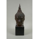 A Thai bronzed metal head bust of Buddha, on a display stand, 35cm high