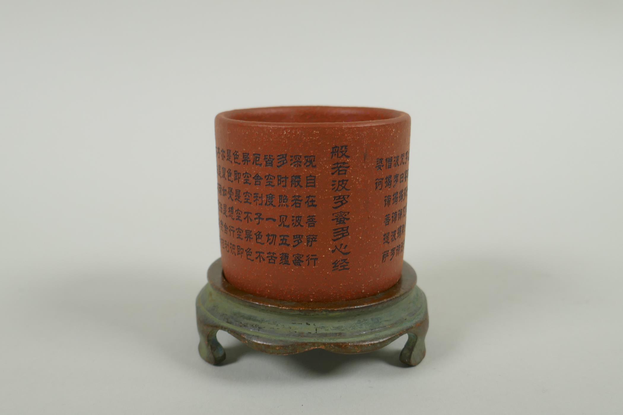 A Chinese YiXing cylinder cup on a bronze stand, decorated with allover character inscription, 6cm