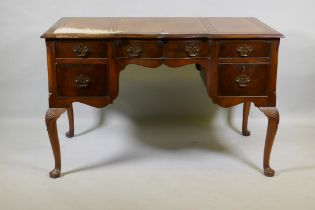 A Georgian style walnut five drawer kneehole desk with inset leather top, raised on cabriole