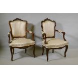 Two C19th French carved beechwood open armchairs, with shaped backs, raised on cabriole supports