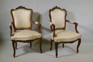 Two C19th French carved beechwood open armchairs, with shaped backs, raised on cabriole supports