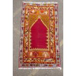 A rich red ground Caucasian rug with prayer mat design and multi-colour borders, 112 x 186cm