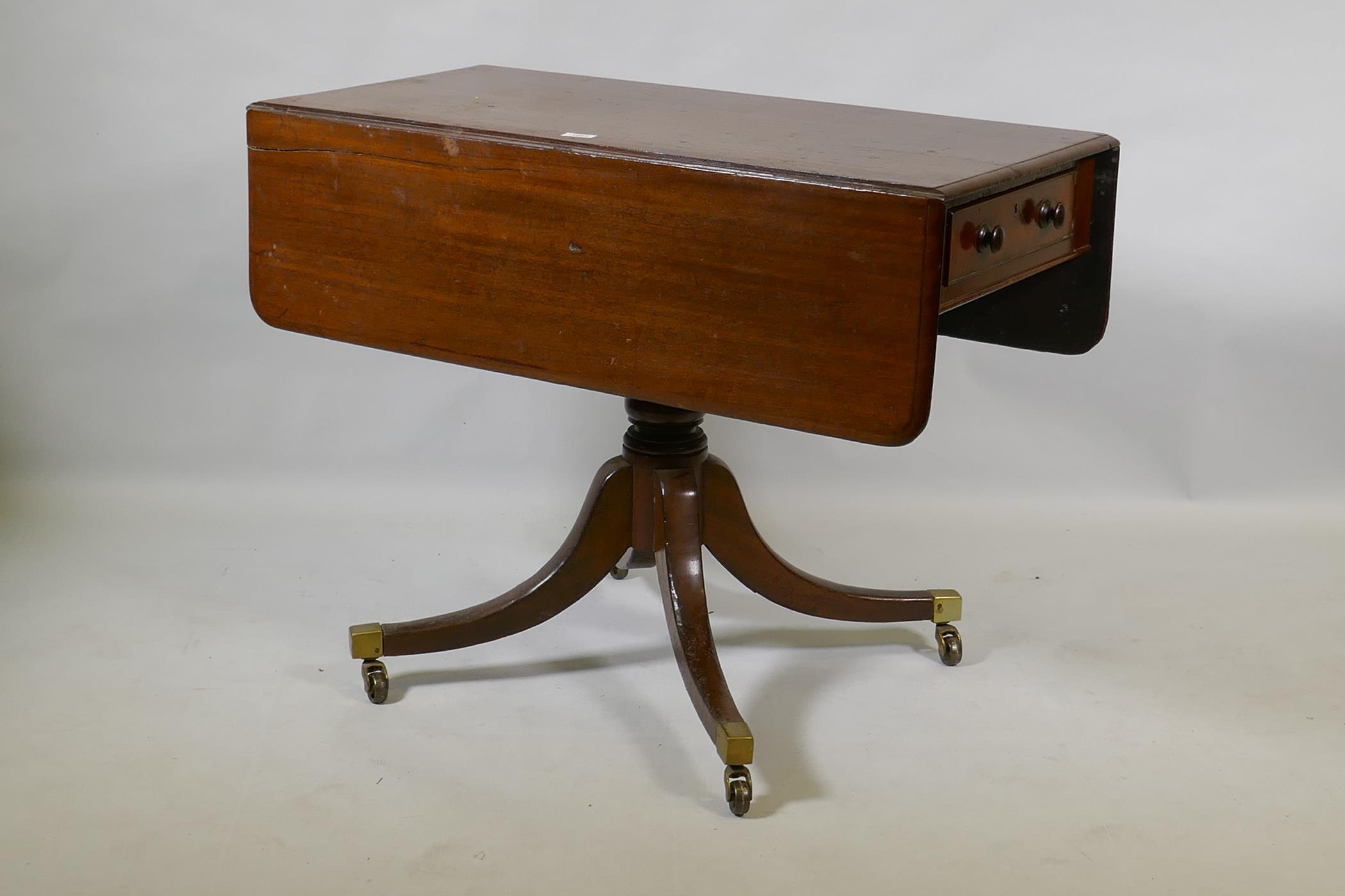 A Georgian mahogany pembroke table with one true and one false drawer, raised on a turned column and