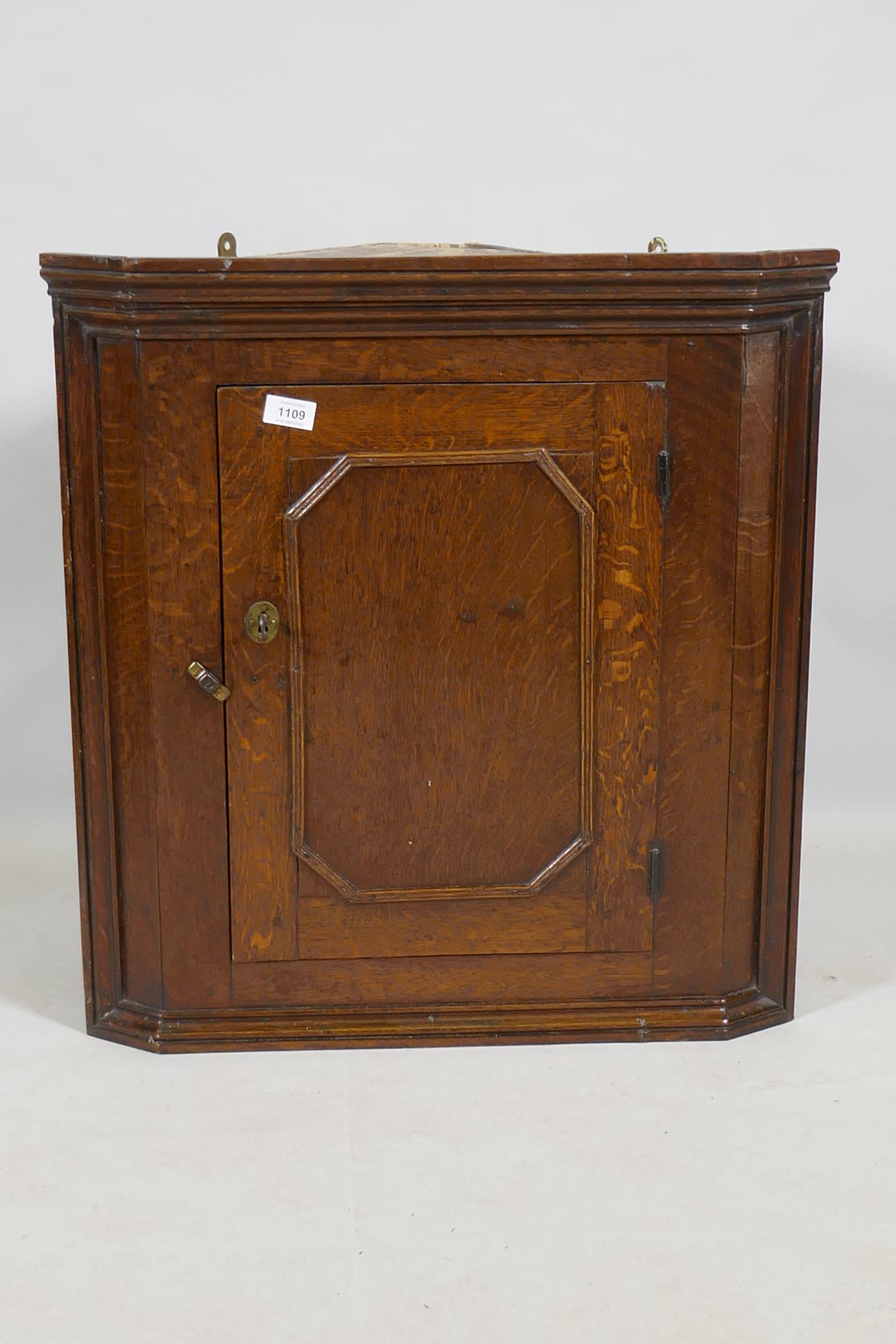 A Georgian oak hanging corner cupboard of small proportions, 66cm high