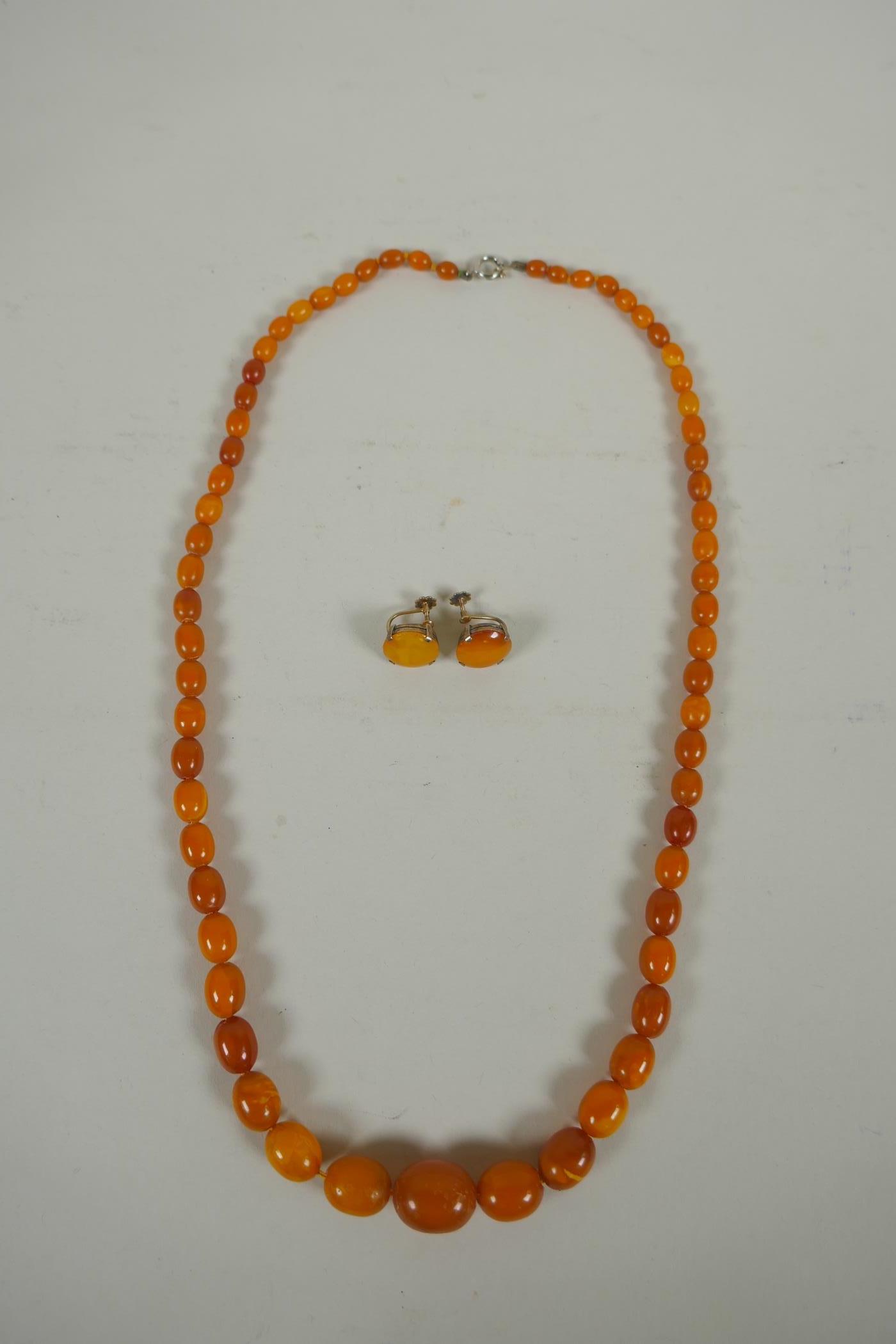 A vintage graduated butterscotch amber necklace and a pair of matching earrings with silver gilt