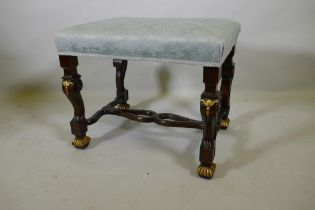 A mahogany stool with carved and parcel gilt decoration, raised on shaped and scrolled supports