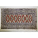 A Persian wool rug with a triple diamond medallion design on a terracotta field with beige