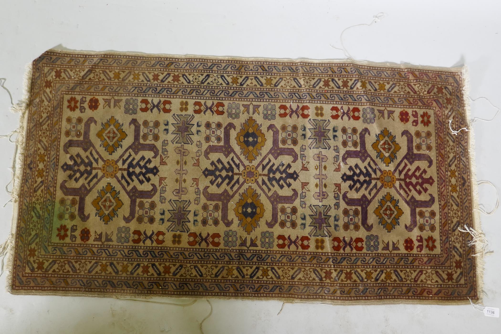 An antique hand woven Oriental rug with geometric designs n a buff coloured field, 68 x 125cm - Image 2 of 3