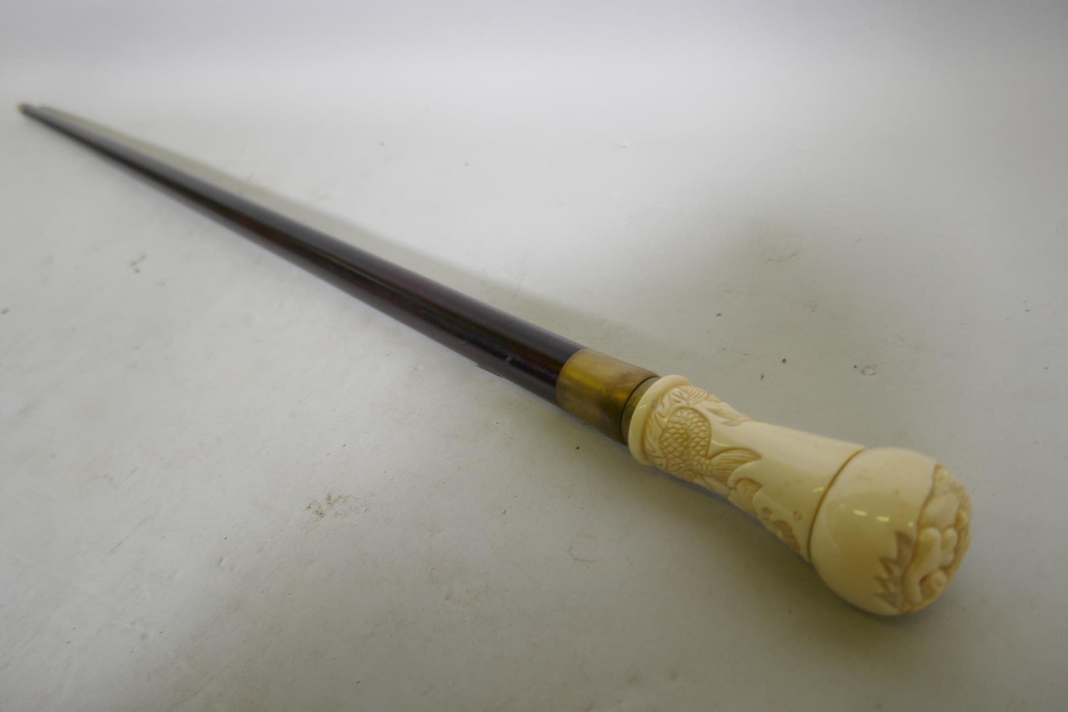 A hardwood walking cane with ivorine handle and mermaid decoration, 88cm long