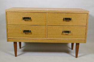 A mid century faded sapele four drawer chest with brass handles, raised on tapering supports, 101