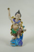 A Chinese Sancai glazed porcelain Lohan standing on a carp, 27cm high
