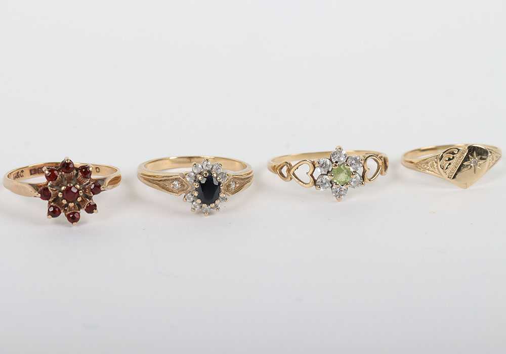 A group of four 9ct rings, including a 9ct ruby flower set ring, with a peridot and diamond ring, a
