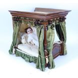 A good Victorian polished wood four poster dolls bed with green silk drapes,