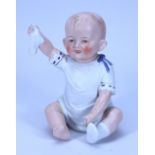 A bisque figurine of a baby holding his sock, German circa 1910,
