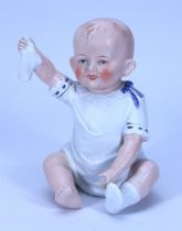 A bisque figurine of a baby holding his sock, German circa 1910,
